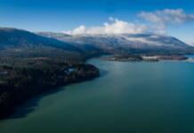 Lake Cerknica pictured against the backdrop of snow dusted hills and some white clouds in a blue sky.